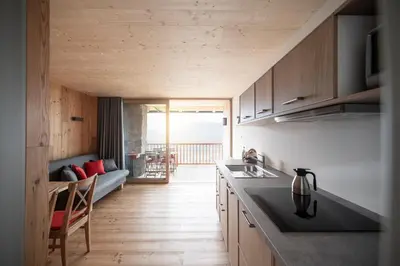 a kitchen with wooden cabinets and a living room at Kristplonerhof in Bolzano