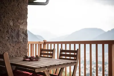 a wooden table and two chairs on a balcony at Kristplonerhof in Bolzano