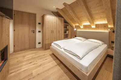 a bedroom with a large white bed and wooden floors at App. Promberger in San Lorenzo di Sebato