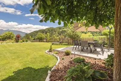 a patio with a table and chairs in a yard at App. Promberger in San Lorenzo di Sebato