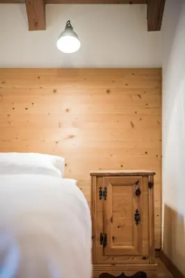 a bedroom with a white bed and a wooden wall at Hotel Hurtmuehle Kronblick in San Lorenzo di Sebato