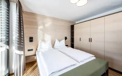 a bedroom with a large white bed and a window at Aparthotel Panorama Living Dolomites in Maranza