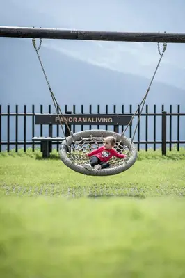 a small child sitting in a tire swing at Aparthotel Panorama Living Dolomites in Maranza