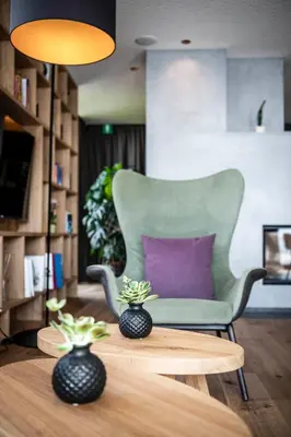 a living room with a green chair and a table at Aparthotel Panorama Living Dolomites in Maranza