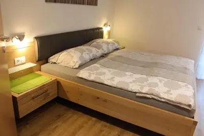 a bed in a room with a wooden bed frame at Appartements Pixner in Saltusio