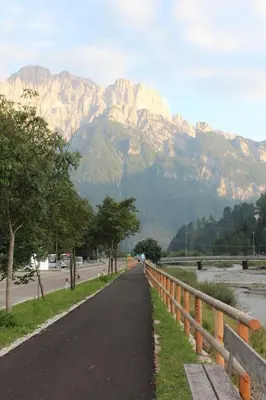 a road with a fence and mountains in the background at Cesa DOLOMITI in Rocca Pietore