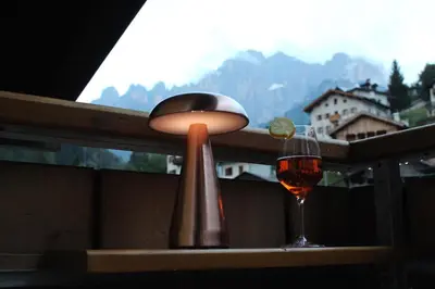 a lamp and a glass of wine on a table at Cesa DOLOMITI in Rocca Pietore