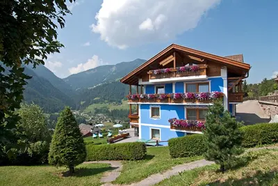 a blue house with flower boxes on the side of it at Hotel Talblick in Ortisei