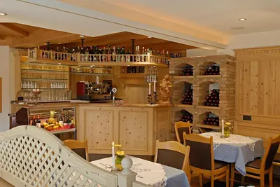 a restaurant with two tables and a bar with wine bottles at Hotel Talblick in Ortisei