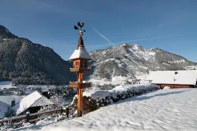 a clock tower in the snow with mountains in the background at Hotel Talblick in Ortisei