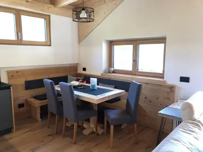 a dining room with a table and chairs and two windows at Cèsa Prinoth in Campitello di Fassa