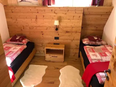 two twin beds in a room with wooden walls at Cèsa Prinoth in Campitello di Fassa