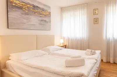a bedroom with a white bed with a painting on the wall at Casa Faloria in Cortina dʼAmpezzo