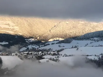 a snow covered mountain with a town in the distance at Forchnerhof Panorama - Dolomitenblick in Rodengo