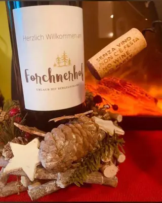 a bottle of wine with a pineapple and a bottle of cheese at Forchnerhof Panorama - Dolomitenblick in Rodengo
