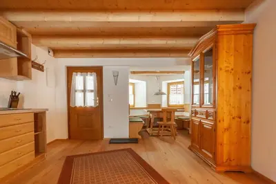 a kitchen with a wooden door and a dining room at Casa Piccolin in Falcade