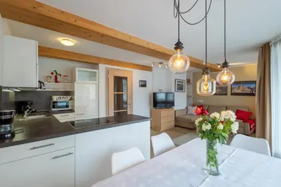 a kitchen and living room with a table with a vase of flowers at Apartments Irene in La Villa