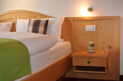 a bedroom with a bed and a table with a night stand at Apartments Dolina in Ortisei