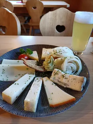 a plate of different types of cheese and a glass of beer at La Stella Alpina in Colle Isarco