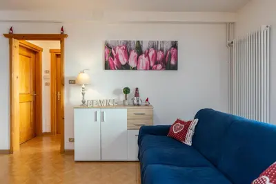a living room with a blue couch and a painting on the wall at Ciasa de Vich in Vigo di Fassa