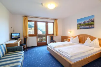a hotel room with two beds and a couch at Hotel Pichlerhof in San Lorenzo di Sebato