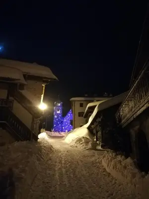 a snow covered street at night with blue lights at Cesa de Conesel in Colle Santa Lucia