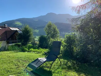 a chair sitting in the grass in a yard at Apartment HaNiLe in Sarntal