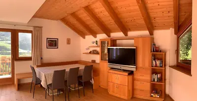 a dining room with a table and chairs and a television at Apartment HaNiLe in Sarntal