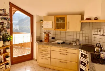 a kitchen with wooden cabinets and a large window at Apartment HaNiLe in Sarntal