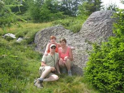 three people sitting on a rock in the grass at Pitterle Hof in Meltina