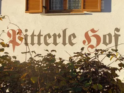 a sign on the side of a building with a bush at Pitterle Hof in Meltina