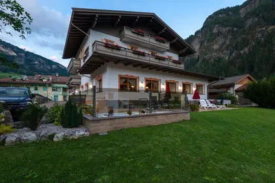 a house in a field with a mountain at Albergo Contrin in Campitello