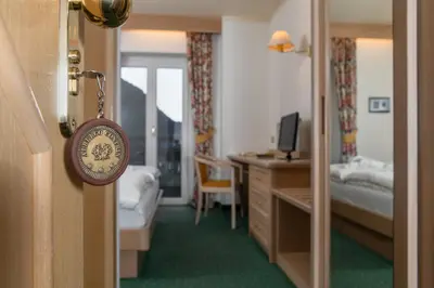 a room with a bedroom with a bed and a desk at Albergo Contrin in Campitello