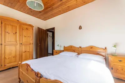 a bedroom with a large bed with a wooden headboard at Casa Carnevali in Pozza di Fassa