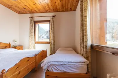 a bedroom with two beds and a window at Casa Carnevali in Pozza di Fassa