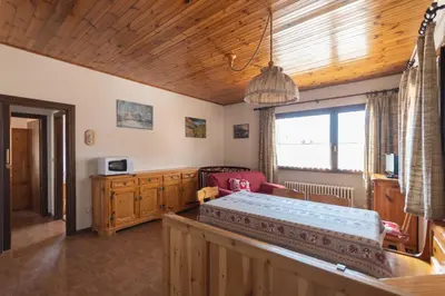a bedroom with a bed and a large window at Casa Carnevali in Pozza di Fassa