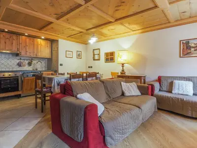 a living room with a couch and a kitchen at Casa Cristina in Campitello di Fassa