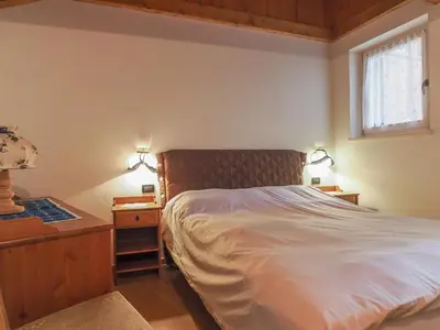 a bedroom with a bed and a nightstand and a window at Casa Cristina in Campitello di Fassa