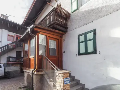a house with a wooden door and stairs on it at Casa Cristina in Campitello di Fassa