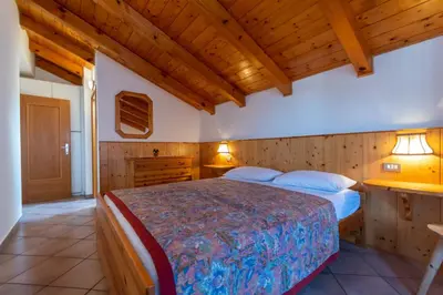 a bedroom with a bed and a wooden ceiling at Casa Fanton in Pozza di Fassa