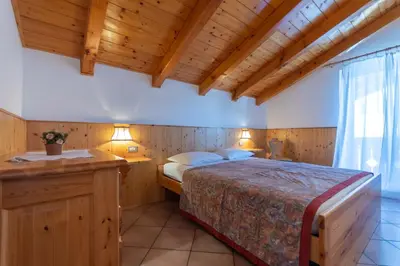 a bedroom with a bed in a room with wooden ceilings at Casa Fanton in Pozza di Fassa
