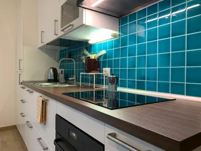 a kitchen with blue tiles on the wall at Casa Turchese in Merano