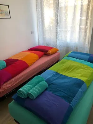 two beds with different colored sheets on them in a room at Casa Turchese in Merano