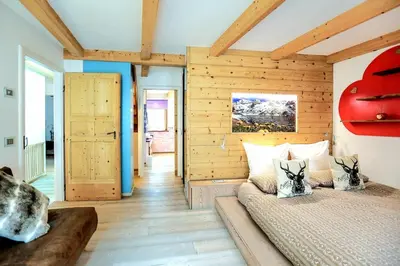 a bedroom with two beds in a room with wooden walls at Chalet Tobià Villa in Canazei
