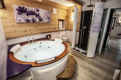a bathroom with a tub in a room with wooden walls at Chalet Tobià Villa in Canazei
