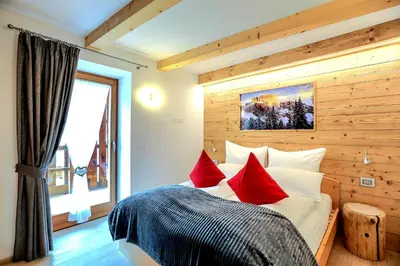 a bedroom with a large bed with red pillows at Chalet Tobià Villa in Canazei