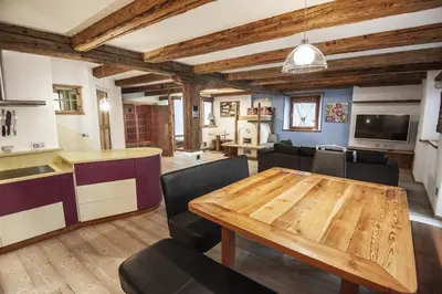 a kitchen and living room with a wooden table and chairs at Chalet Tobià Villa in Canazei