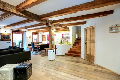 a living room with a black couch and wooden ceilings at Chalet Tobià Villa in Canazei