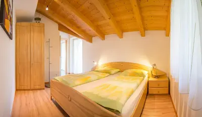 a bedroom with a large bed and a wooden ceiling at St. Urbanhof in Termeno