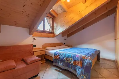 a bedroom with a bed and a couch at Casa Sartori in Pozza di Fassa